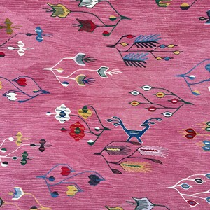 May include: A pink rug with a repeating pattern of stylized flowers and leaves in shades of blue, red, yellow, and white.