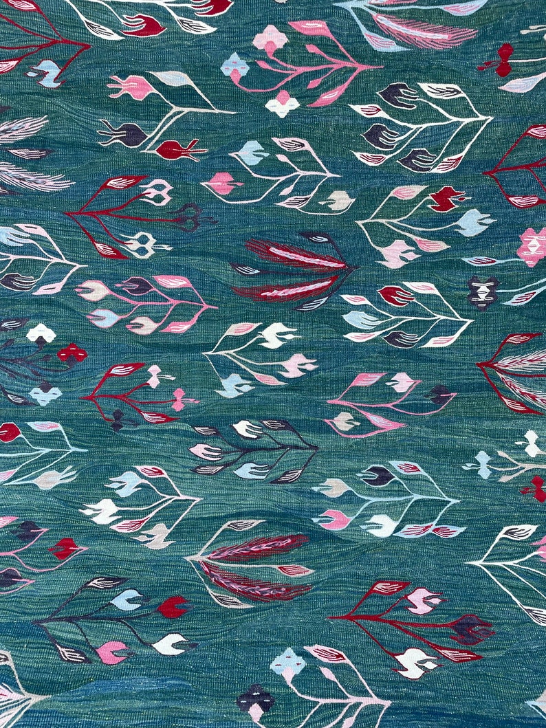 May include: Teal fabric with a repeating pattern of stylized floral designs in shades of pink, white, red, and black.