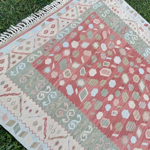 K&ouml;nnte beinhalten: Ein mehrfarbiger Teppich mit geometrischem Muster. Der Teppich hat einen Fransenrand und ist aus weichem, gewebtem Material.