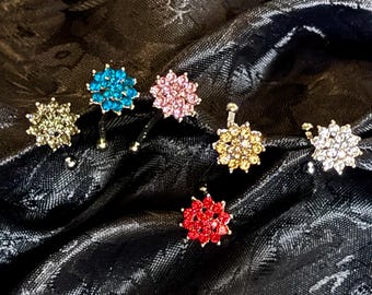 May include: Six sparkly hair clips in a variety of colors, including turquoise, pink, gold, red, and clear. The clips are arranged on a black fabric background.
