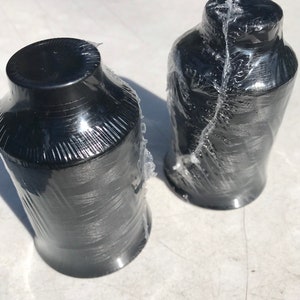 May include: Two spools of black thread wrapped in clear plastic.