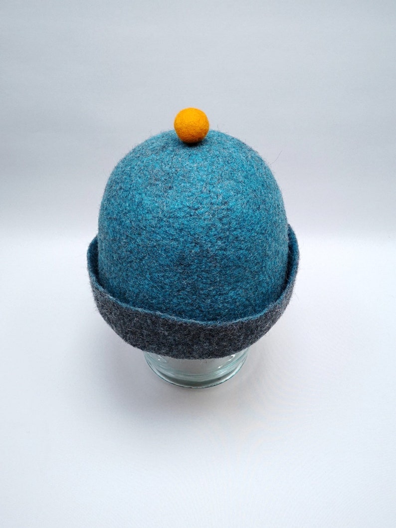 Rough edged graphite grey or teal blue bobble close fitting beanie hat natural wool saunaoutdoors charcoal gray cloche with a orange bobble
