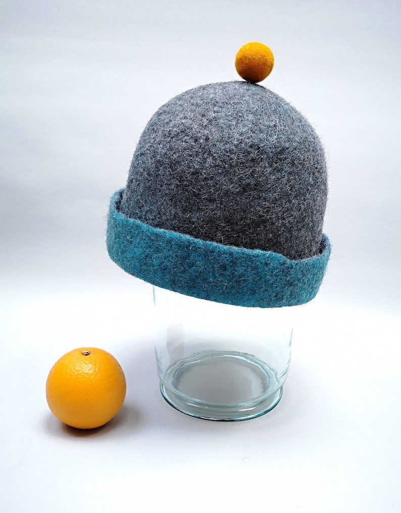 Rough edged graphite grey or teal blue bobble close fitting beanie hat natural wool saunaoutdoors charcoal gray cloche with a orange bobble