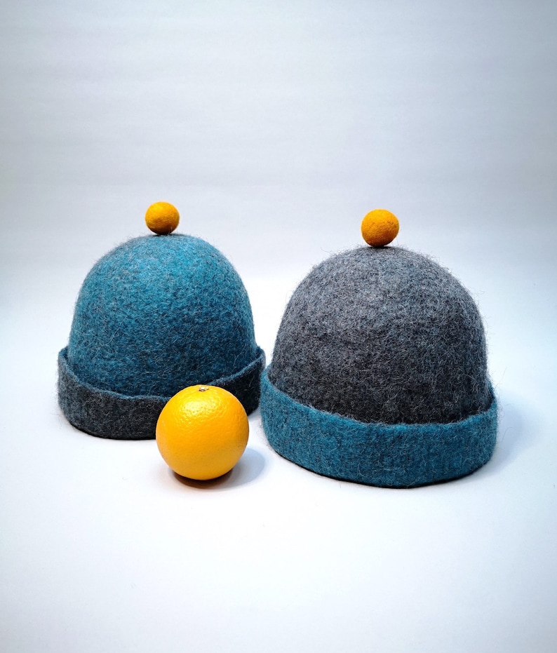 Rough edged graphite grey or teal blue bobble close fitting beanie hat natural wool saunaoutdoors charcoal gray cloche with a orange bobble