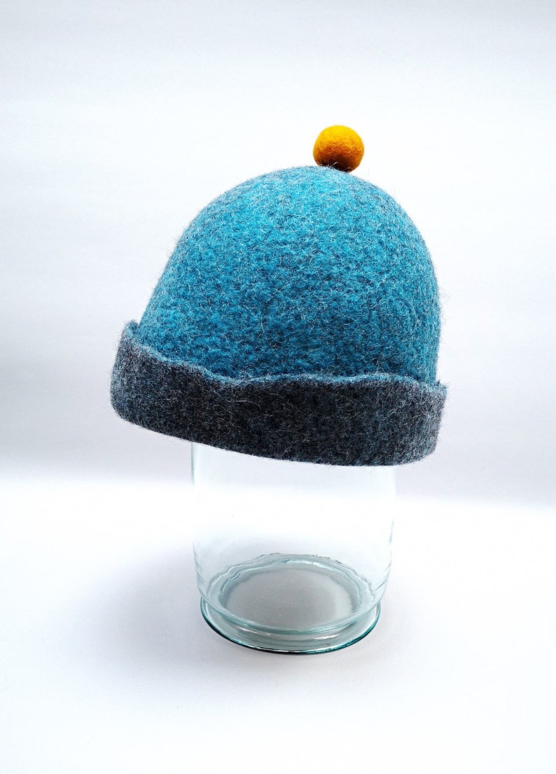 Rough edged graphite grey or teal blue bobble close fitting beanie hat natural wool saunaoutdoors charcoal gray cloche with a orange bobble
