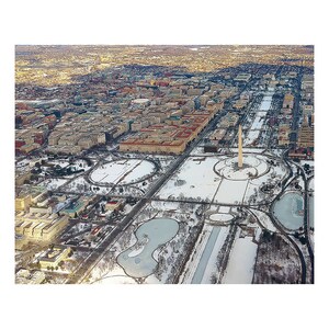 May include: An aerial view of Washington, D.C. in the winter, showing the Washington Monument and the National Mall covered in snow.
