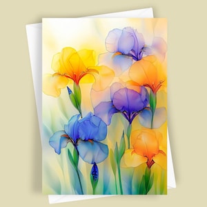 May include: Greeting card featuring watercolor iris flowers in shades of yellow, orange, blue, and purple. The flowers have delicate, translucent petals and green stems. The card is set against a soft, yellow and white background, with a white envelope.