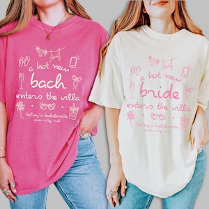 May include: Two t-shirts, one in pink and one in cream, with matching text and graphics. The pink shirt says "a hot new bach enters the villa" and the cream shirt says "a hot new bride enters the villa". Both shirts have beach-themed graphics.