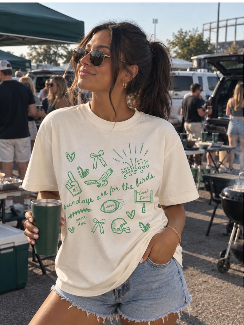 Pu&ograve; includere: Una t-shirt a maniche corte color crema con illustrazioni grafiche verdi a tema football americano, tra cui un casco, un pallone, un palo della porta, un dito di gommapiuma e fiocchi, con la scritta "sundays are for the birds" in verde.