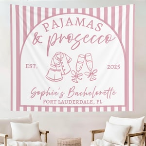 May include: A pink and white striped tapestry with the words "PAJAMAS & prosecco" in a decorative arch. The tapestry includes illustrations of pajamas and champagne flutes, with the text "Sophie's Bachelorette, Fort Lauderdale, FL."