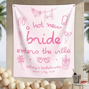 May include: A light pink rectangular fabric banner featuring dark pink line art illustrations of a bikini, flip-flops, a smartphone, a cocktail, a bow, a palm tree, and heart-shaped sunglasses with the text a hot new bride enters the villa.