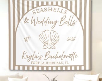 Peut inclure: Une tapisserie à rayures beiges et blanches avec le texte "Seashells & Wedding Bells" et "Kayla's Bachelorette Fort Lauderdale, FL". Un motif de coquillage est centré sur la tapisserie. L'année 2025 est également affichée.