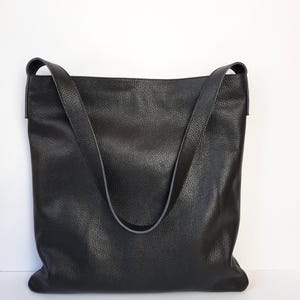 May include: A black leather tote bag with a single strap. The bag has a textured surface and a slightly slouched look.
