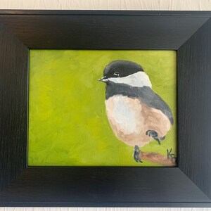 Puede incluir: Una pintura enmarcada de un carbonero común posado en una rama sobre un fondo verde.