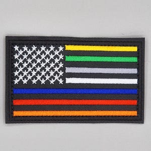 Könnte beinhalten: Ein gestickter Aufnäher mit einer dünnen blauen Linie der amerikanischen Flagge mit zusätzlichen farbigen Streifen, die verschiedene Ersthelfergruppen repräsentieren. Die Flagge ist schwarz mit weißen Sternen und gelben, grünen, grauen, weißen, blauen, roten und orangefarbenen Streifen.