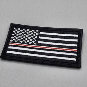 May include: Black and white embroidered American flag patch with a thin red stripe across the middle.