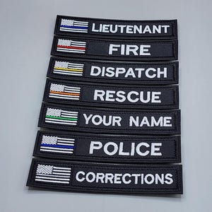 May include: Black embroidered patches with white text and American flag accents. Patches include "LIEUTENANT", "FIRE", "DISPATCH", "RESCUE", "YOUR NAME", "POLICE", and "CORRECTIONS". Ideal for uniforms or gear.