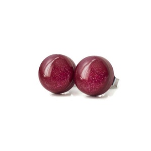 May include: A pair of round, burgundy stud earrings with a glittery finish.