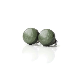 Op de afbeelding: Een paar groene oorbel studs met een glinsterende afwerking. De oorbellen zijn gemaakt van metaal en hebben een ronde vorm.