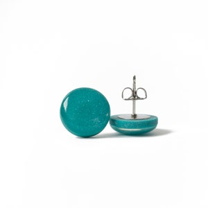 May include: A pair of teal blue stud earrings with a silver post and butterfly back.