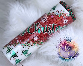 May include: A red and white glitter tumbler with a green "Merry Christmas" design and green and white glitter snowflakes. The tumbler has a green and white glitter lid with rhinestones.