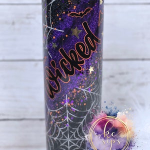 K&ouml;nnte beinhalten: Ein schwarzer und lilafarbener Becher mit einem Spinnennetz-Design und dem Wort "Wicked" in orangefarbener Schrift. Der Becher hat eine glitzernde Oberfl&auml;che und einen schwarzen Deckel mit Strasssteinen.