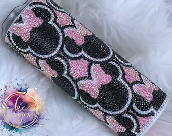 May include: A white tumbler with a black and pink rhinestone design featuring multiple Mickey Mouse heads.