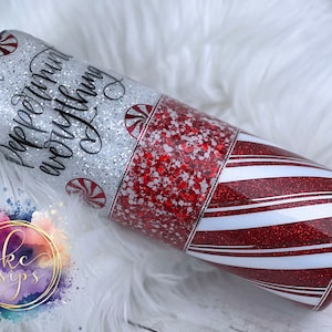 Könnte beinhalten: Ein rot-weiß gestreifter Becher mit silbernem Glitzer und dem Text "Peppermint everything" in schwarzer Schrift. Der Becher hat ein Zuckerstangen-Design.
