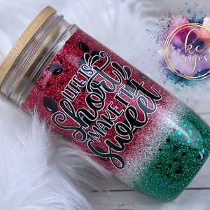 Könnte beinhalten: Ein roter, weißer und grüner Glitzerbecher mit Bambusdeckel. Der Becher hat den Text "Life is short make it sweet" aufgedruckt.