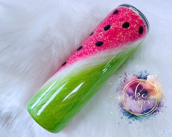 May include: A green and pink glitter tumbler with a watermelon design. The tumbler has black seeds and a white swirl design.