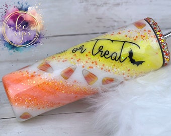 May include: A yellow and orange glitter tumbler with a white and orange candy corn design. The tumbler has the words "Trick or Treat" written on it and a black bat silhouette.