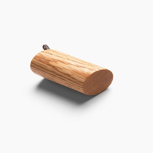 May include: A wooden hook with a rounded end and a screw for mounting. The hook is made of light brown wood with a natural grain pattern.