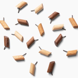 May include: A collection of 15 wooden wall hooks in two different wood tones. The hooks are scattered on a white background.