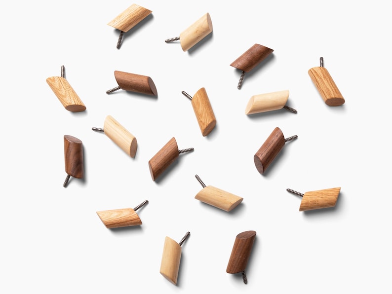 May include: A collection of 15 wooden wall hooks in two different wood tones. The hooks are scattered on a white background.