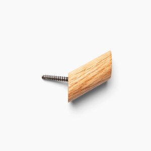 May include: A wooden wall hook with a screw for mounting. The hook is light brown and has a natural wood grain.