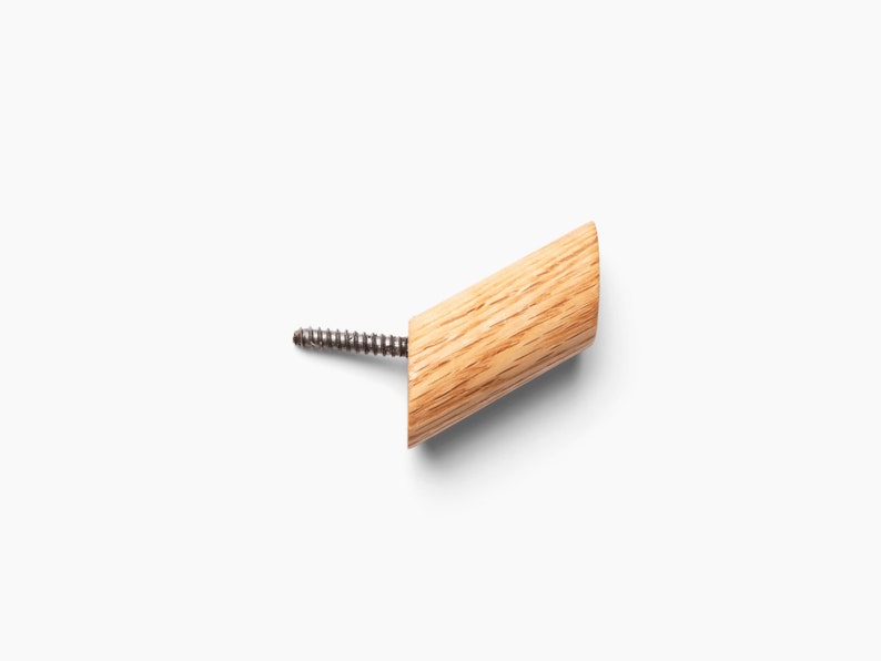 May include: A wooden wall hook with a screw for mounting. The hook is light brown and has a natural wood grain.