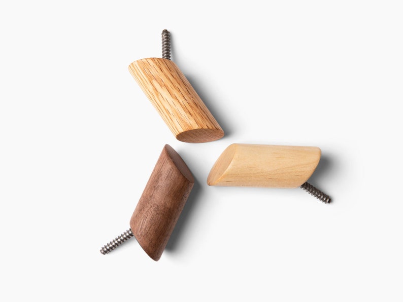 May include: Three wooden wall hooks with screws. The hooks are in different shades of brown, including light brown, medium brown, and dark brown.