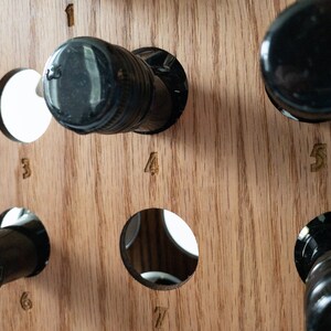 Puede incluir: Estante de vino de madera con siete ranuras para botellas. El estante est&aacute; hecho de madera marr&oacute;n claro y tiene forma triangular. Las ranuras est&aacute;n numeradas del 1 al 7.