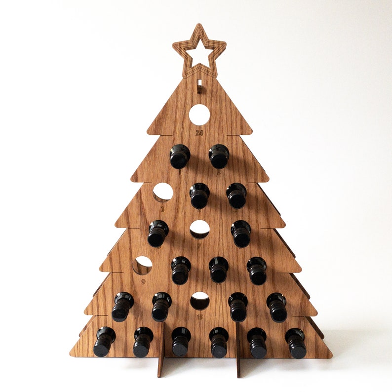 Puede incluir: Porta botellas de vino de madera con forma de &aacute;rbol de Navidad con 24 ranuras para botellas peque&ntilde;as. El &aacute;rbol est&aacute; hecho de madera marr&oacute;n claro y tiene una estrella en la parte superior.