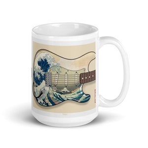 K&ouml;nnte beinhalten: Wei&szlig;e Keramiktasse mit einem Motiv einer Vintage-E-Gitarre mit einem Design, das von der Gro&szlig;en Welle vor Kanagawa von Hokusai inspiriert ist. Die Gitarre ist mit einem blauen und wei&szlig;en Wellendesign bemalt.