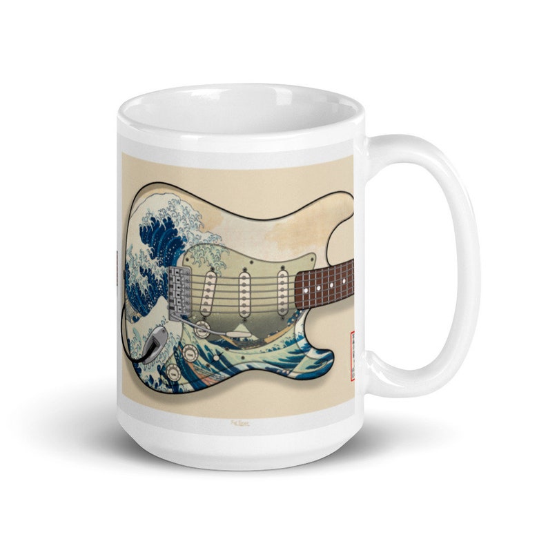 K&ouml;nnte beinhalten: Wei&szlig;e Keramiktasse mit einem Motiv einer Vintage-E-Gitarre mit einem Design, das von der Gro&szlig;en Welle vor Kanagawa von Hokusai inspiriert ist. Die Gitarre ist mit einem blauen und wei&szlig;en Wellendesign bemalt.