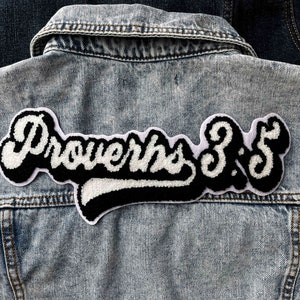 Könnte beinhalten: Eine Jeansjacke mit einem weißen und schwarzen gestickten Aufnäher, auf dem "Sprüche 3:5" steht.