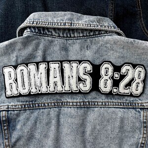 May include: A denim jacket with a black and white embroidered patch that says "ROMANS 8:28".