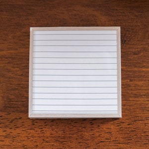 May include: A white lined notepad with a wooden frame.
