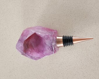 Resin wine bottle stopper with embedded pink floral artwork  and copper coloured stopper