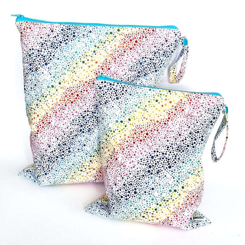 May include: Two reusable, waterproof bags with a white background and a colorful dot pattern. The bags have a rainbow of colors, including red, orange, yellow, green, blue, and purple. Each bag has a blue zipper and a small fabric loop.