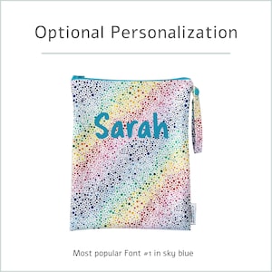 May include: A personalized zippered pouch with a rainbow dotted pattern. The name "Sarah" is embroidered in sky blue. The pouch has a teal zipper and a matching wrist strap. Text at the top reads "Optional Personalization".