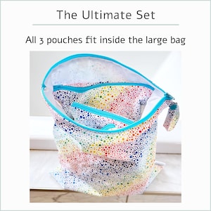 May include: The Ultimate Set of three colorful dot-patterned pouches. The largest bag has a turquoise zipper and trim, with two smaller pouches inside. The text reads, "All 3 pouches fit inside the large bag."