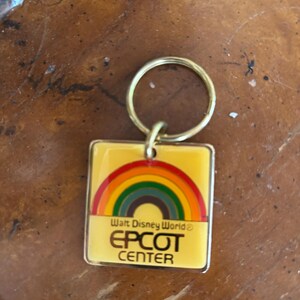 May include: A yellow metal keychain with a rainbow and the text "Walt Disney World® EPCOT CENTER".