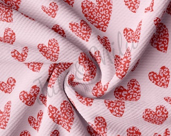 May include: Pink fabric with a repeating pattern of red hearts with a leopard print design.